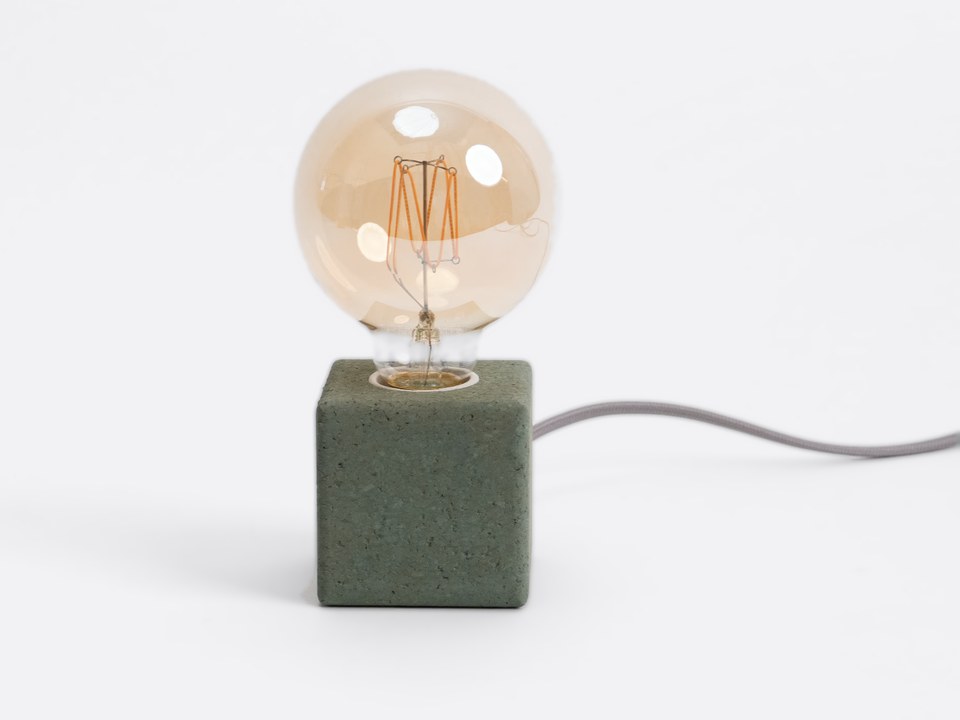 The Spring Green Cube Lamp with an amber globe bulb and a grey fabric cable.